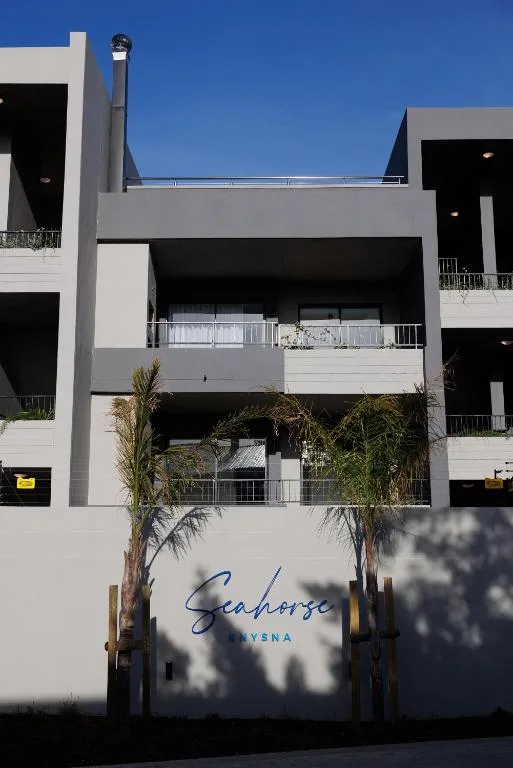 Modern multi-story apartment building facade with balconies and palm trees