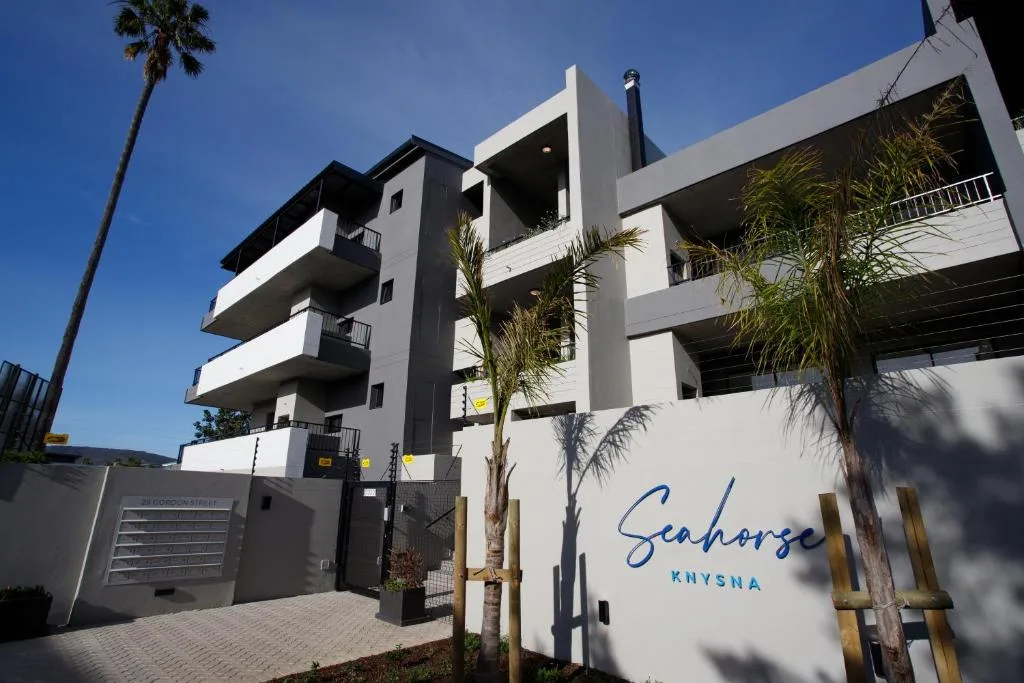 Modern white apartment building with black accents and palm trees, Knysna