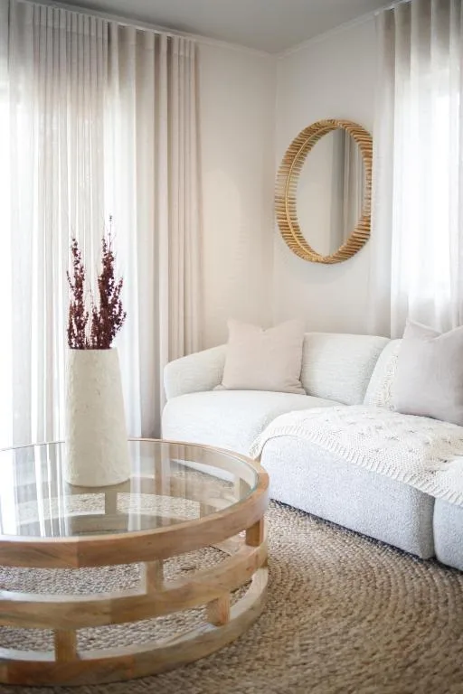 Bright, minimalist lounge with cream sofa, wooden mirror, and natural light