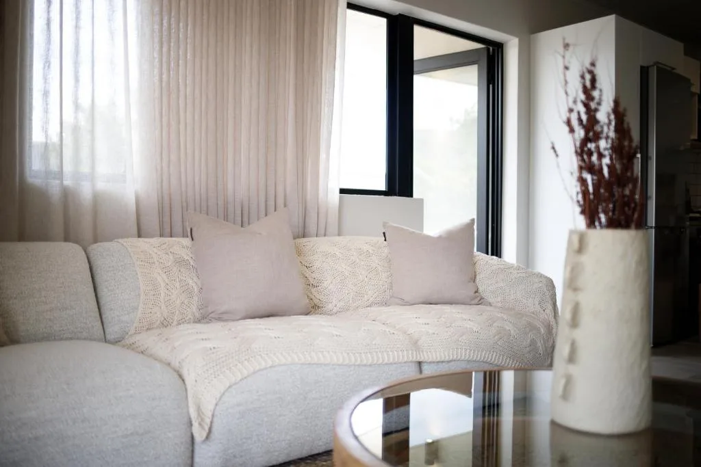Bright modern lounge with cream curved sofa and decorative cushions