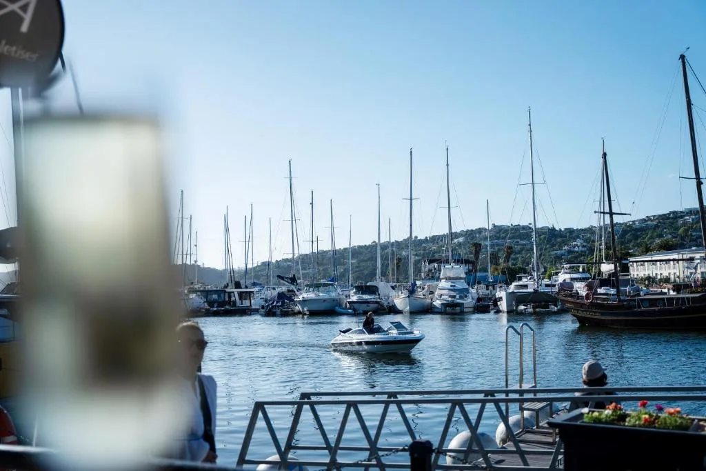 Scenic harbor view with moored sailboats and coastal hills beyond