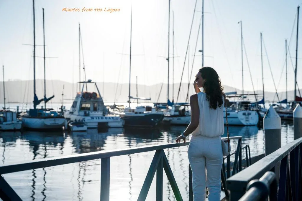 Woman overlooking moored sailboats and lagoon waters from wooden deck