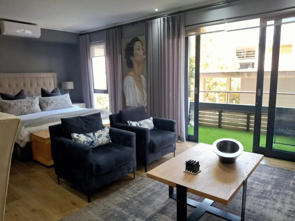 Modern studio bedroom with seating area and deck access overlooking garden