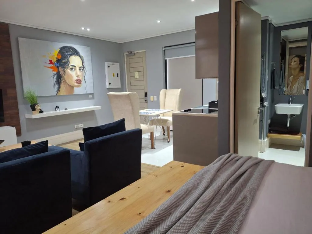 Modern studio bedroom with bed, lounge seating, and ensuite bathroom visible