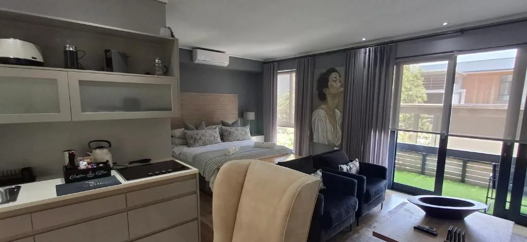Modern bedroom with queen bed, kitchenette, and sliding glass doors to deck