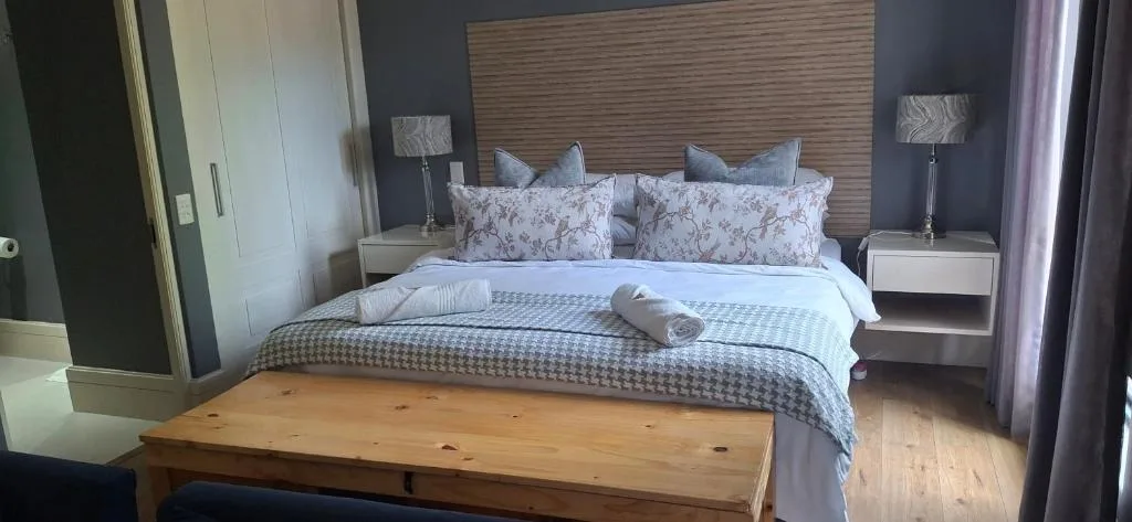 Modern bedroom with queen bed, patterned pillows, wood headboard, and side lamps