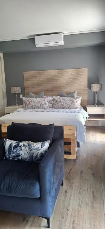 Modern bedroom with wooden headboard, blue accent walls, and air conditioning unit