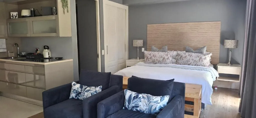 Studio bedroom with queen bed, wood headboard, and navy lounge seating area