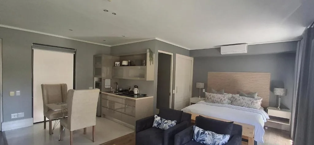 Modern studio bedroom with kitchenette, queen bed, and lounge seating area