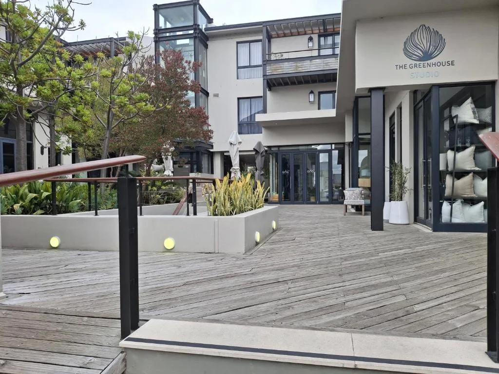 Modern wooden deck with metal railings, landscaping, and building entrance