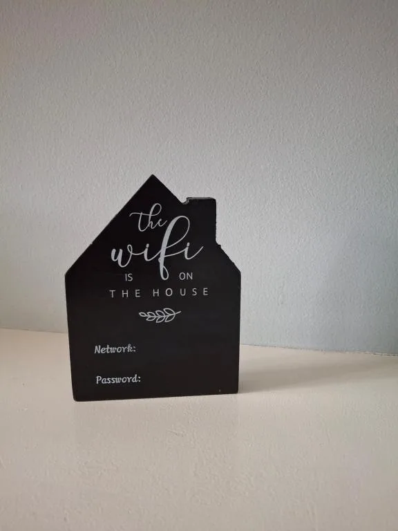 Black house-shaped sign displaying WiFi network and password information