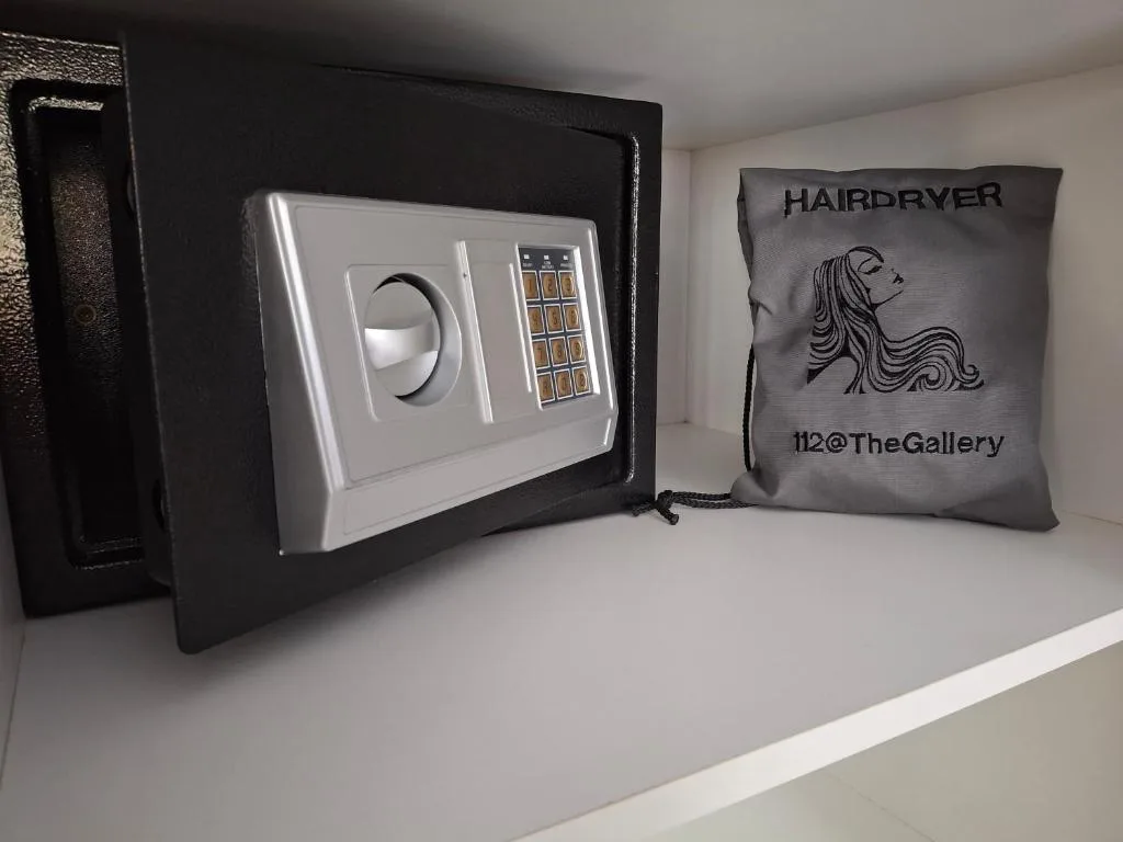Wall-mounted safe and hairdryer amenities displayed on bathroom shelf