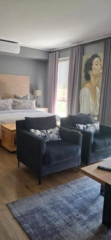 Modern lounge with dark armchairs and portrait artwork on wall