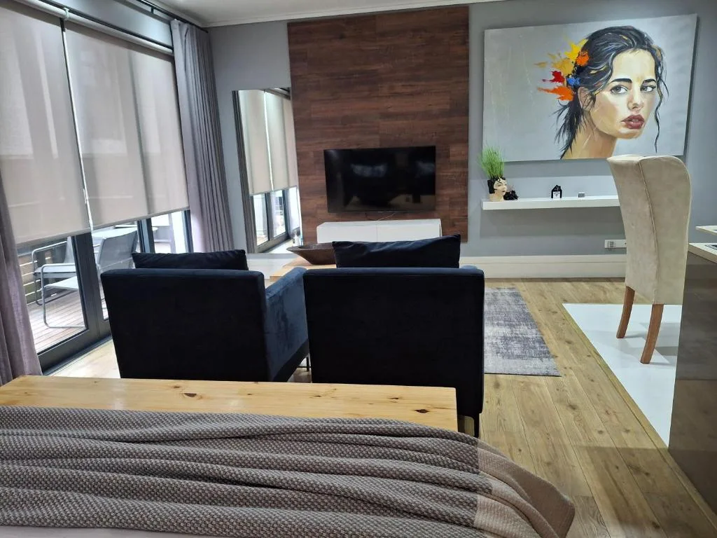 Modern lounge with black sofas, wooden TV feature wall, and contemporary artwork
