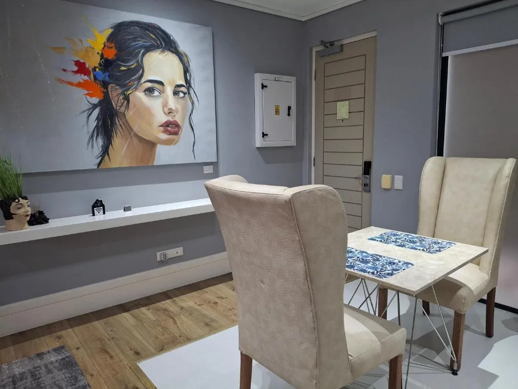Modern lounge area with upholstered chairs, colorful portrait artwork, and contemporary furnishings