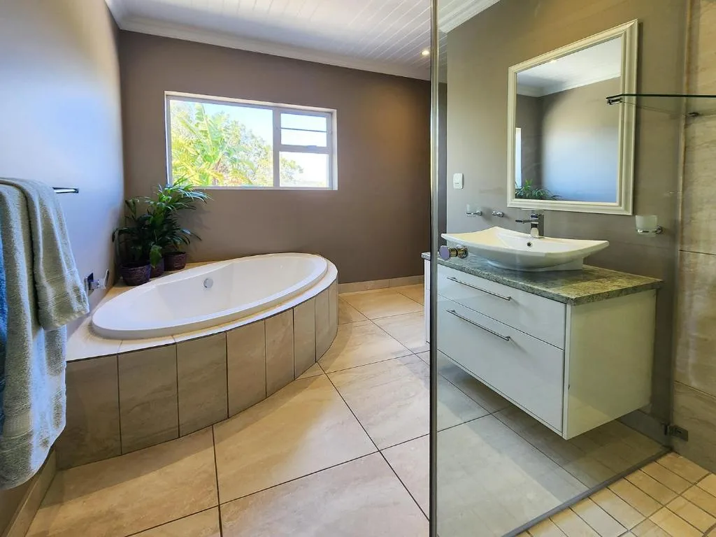 Spacious bathroom with oval soaking tub, vessel sink, and garden view window