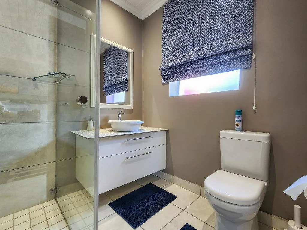 Modern bathroom with shower enclosure, white vanity sink, and toilet