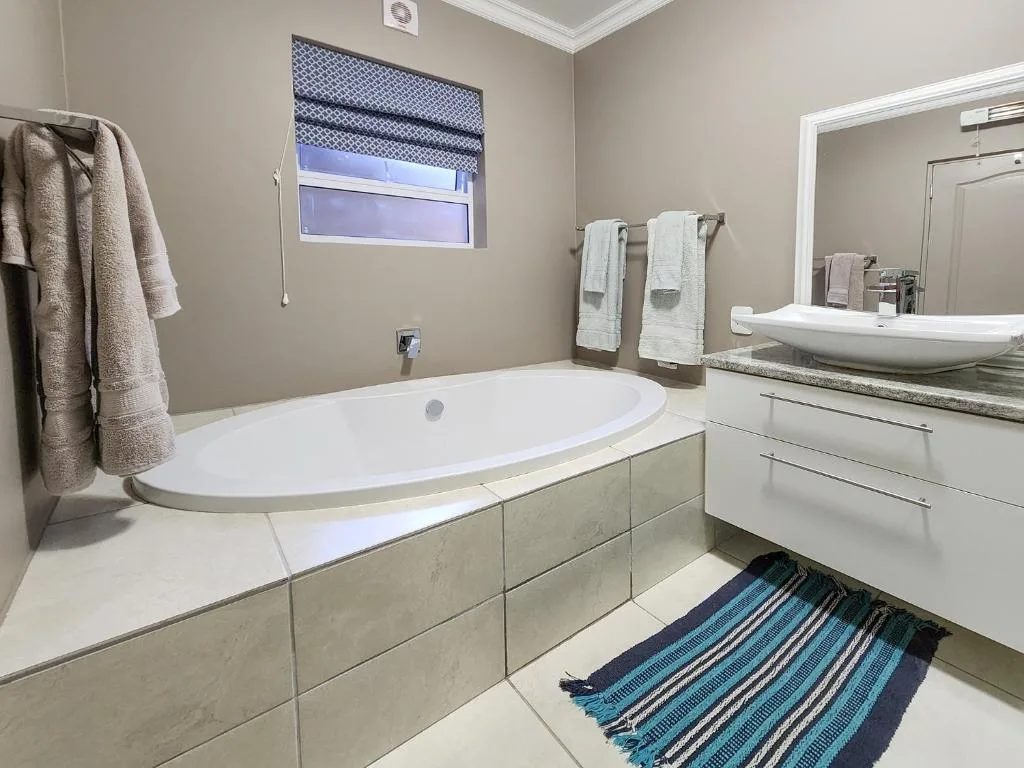 Modern bathroom with sunken bathtub, dual vanity, and window overlooking exterior
