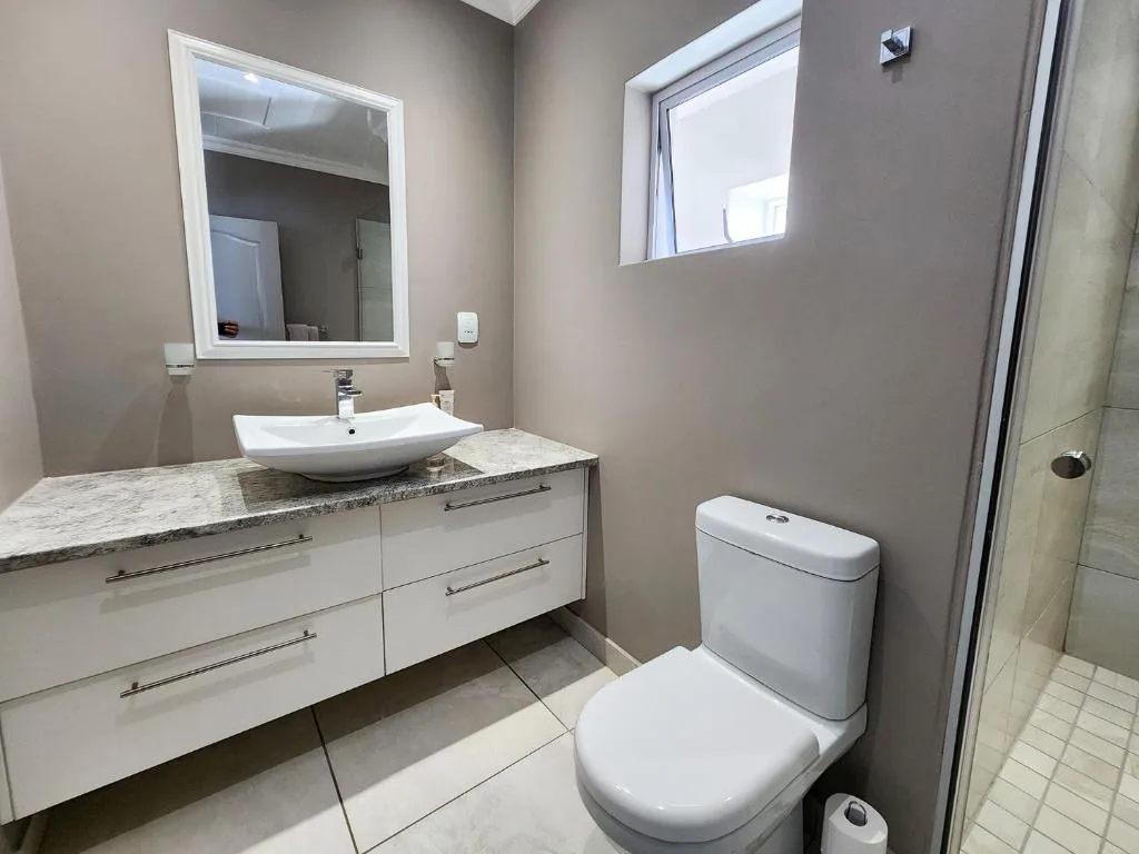 Modern bathroom with white vanity sink, toilet, and large mirror