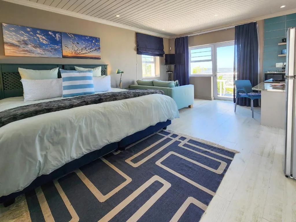 Modern bedroom with queen bed, sea view artwork, and glass door balcony access