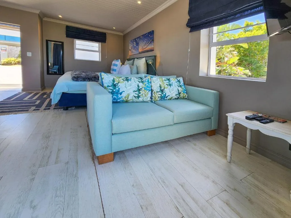 Spacious bedroom with light blue sofa, queen bed, and garden views