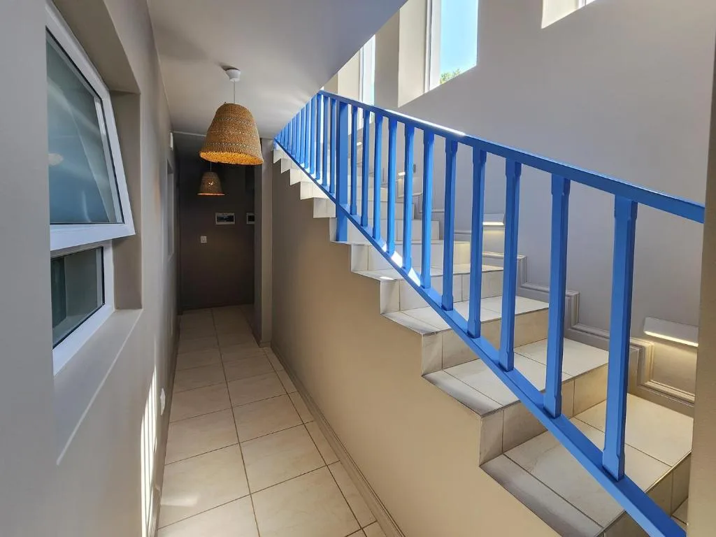 Modern interior hallway with bright blue staircase railing and pendant lighting