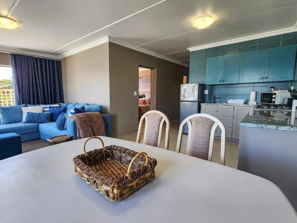 Open-plan dining and kitchen area with white table, woven basket centerpiece