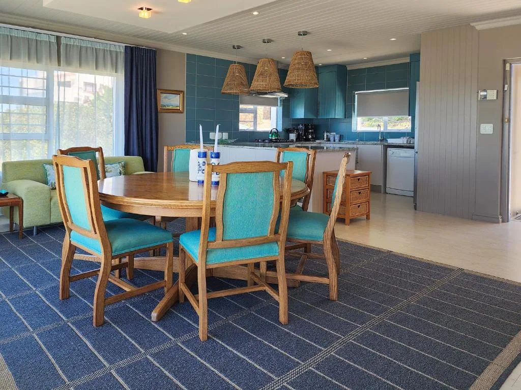 Open-plan dining area with wooden round table and turquoise chairs