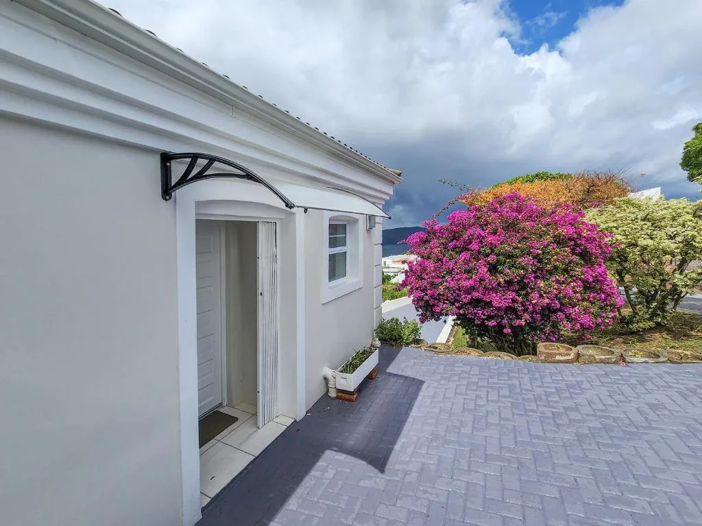 White villa entrance with modern awning and vibrant magenta bougainvillea blooms