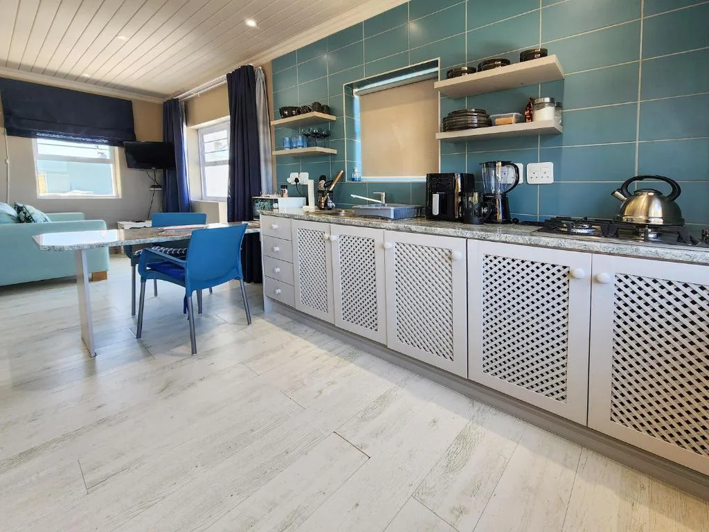 Modern kitchen with turquoise tile backsplash, white cabinetry, and granite countertops
