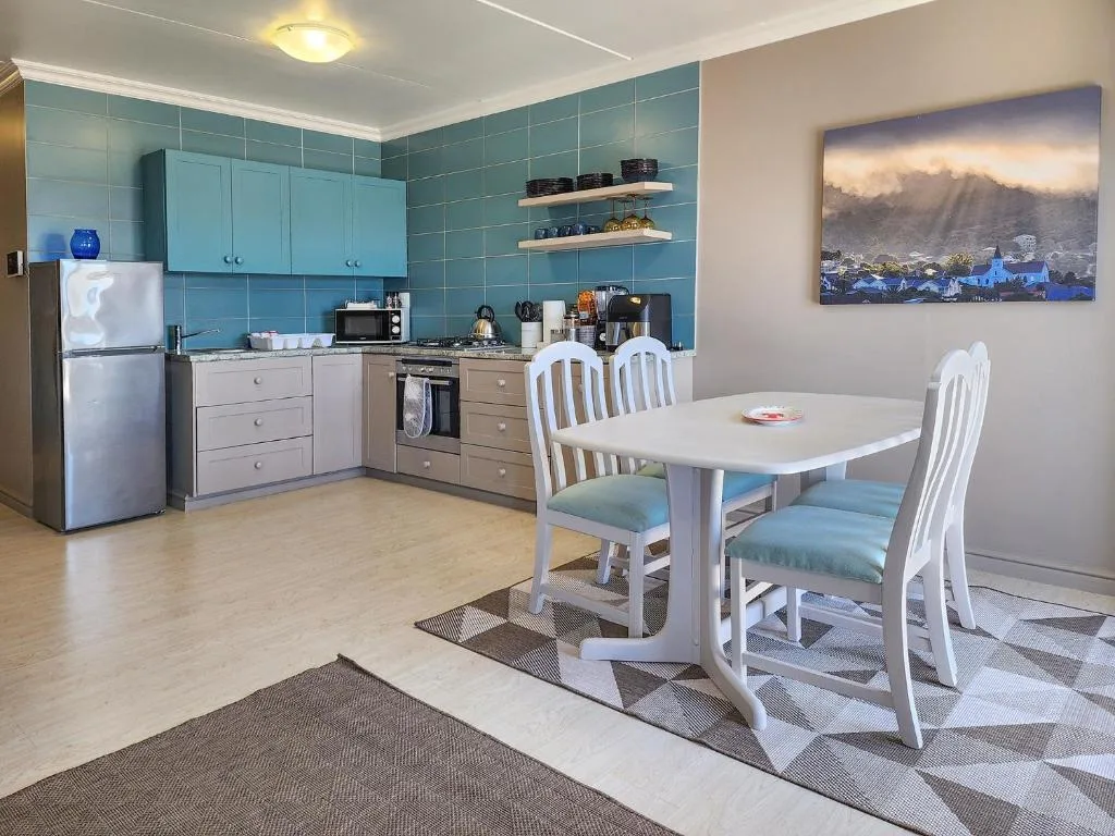 Modern kitchen with turquoise tiled backsplash, stainless steel appliances, and white dining table