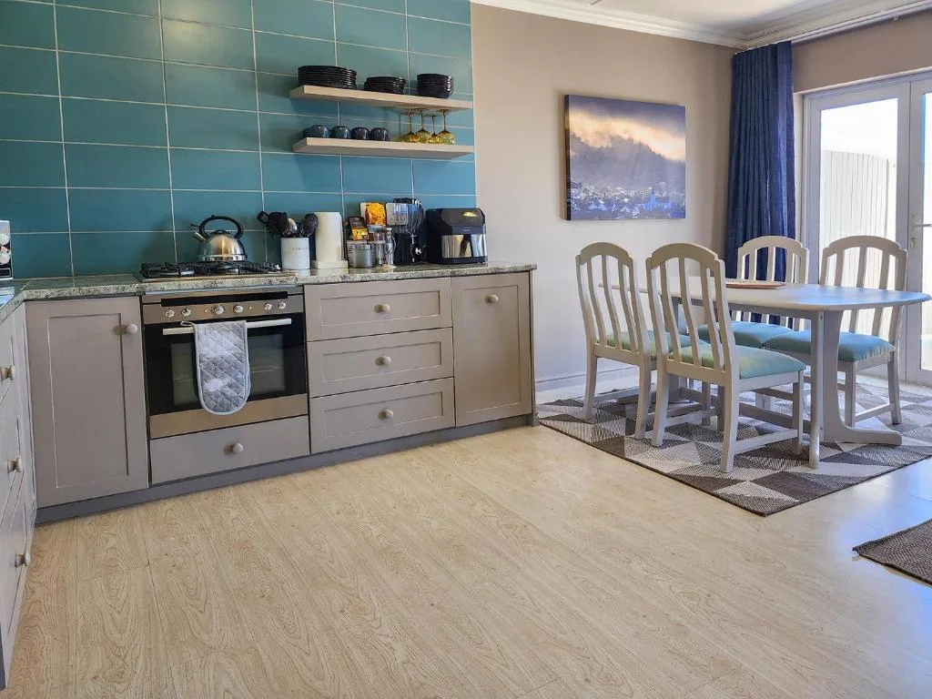 Modern kitchen with turquoise tile backsplash, stove, and dining area beyond