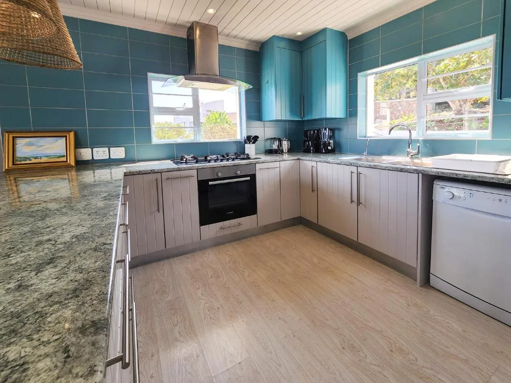 Modern kitchen with turquoise tiled walls, stainless appliances, and granite countertops