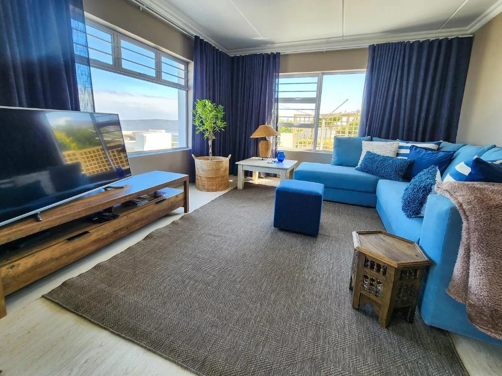 Bright living room with blue sofa, TV, ocean views through large windows