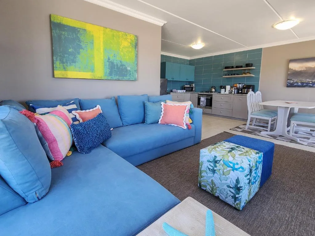 Bright open-plan lounge with blue modular sofa and kitchen visible behind