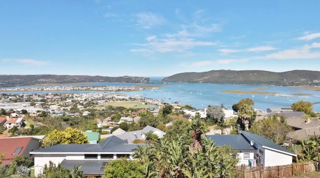 Coastal lagoon and town nestled between green hills under blue sky