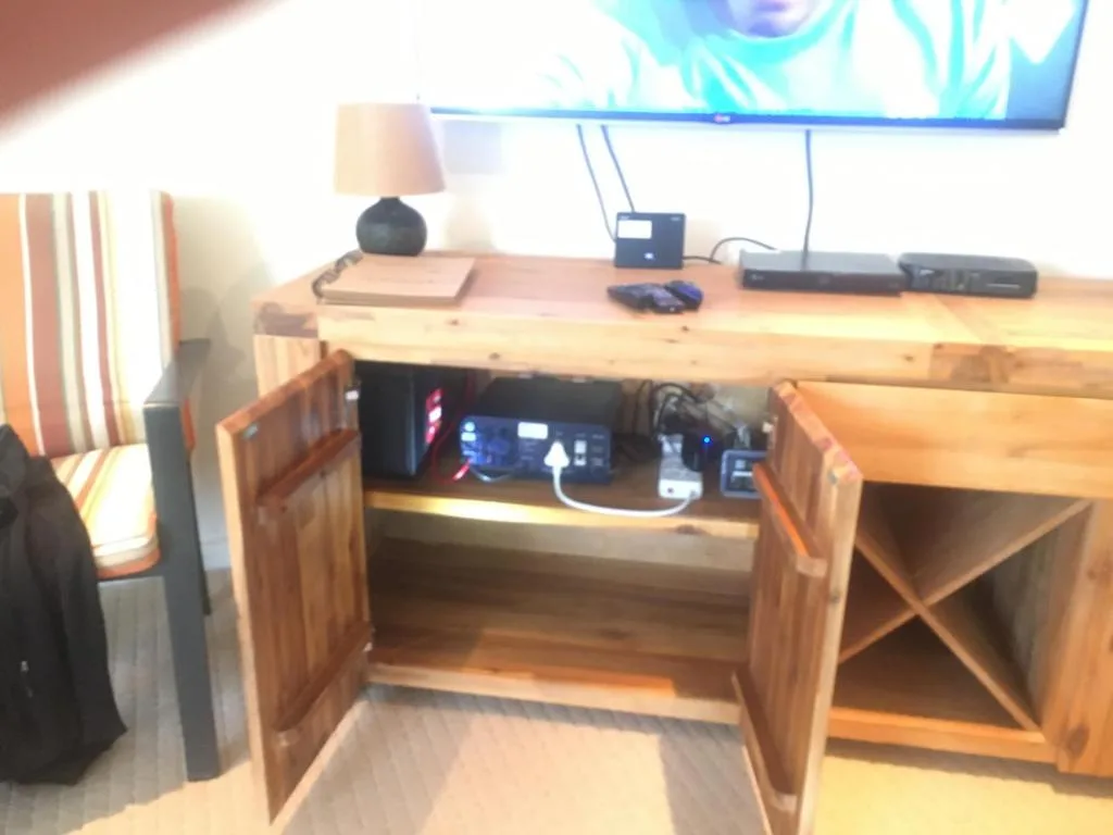 Wooden desk with open cabinet doors revealing entertainment equipment and electronics