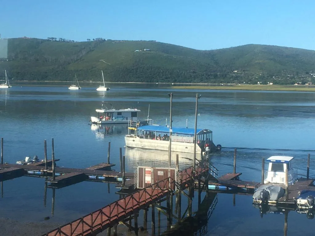 Scenic lagoon view with moored boats and forested hills beyond