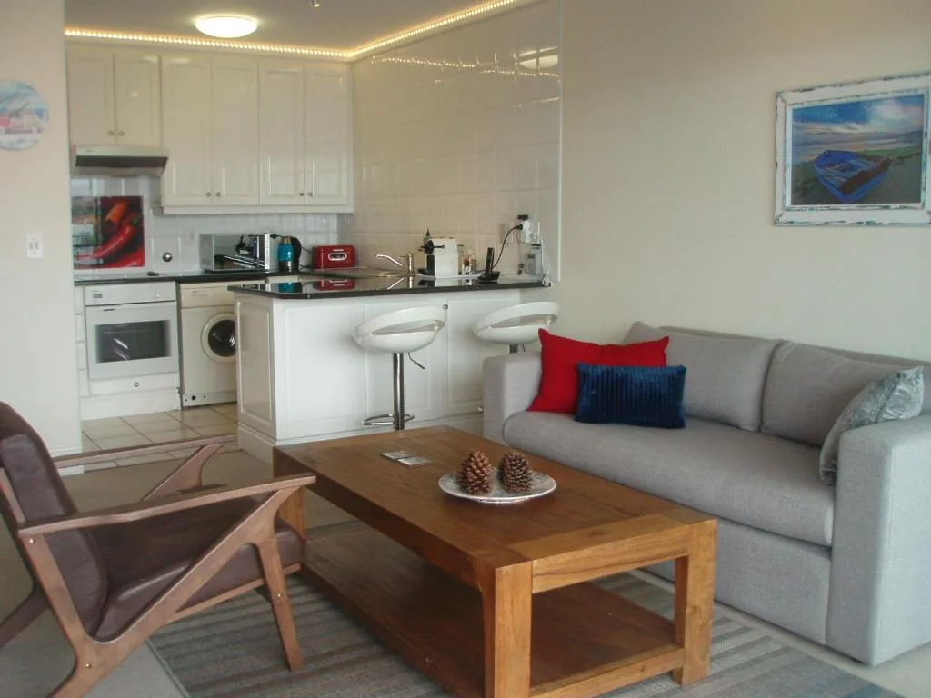 Open-plan living room with gray sofa, wooden coffee table, and kitchen area