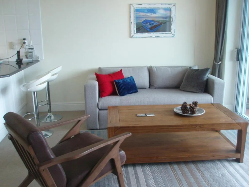 Modern lounge with gray sofa, wooden coffee table, and coastal artwork