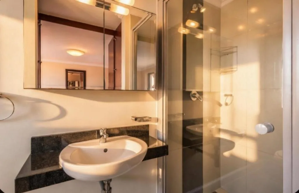 Modern bathroom with round basin sink, mirror cabinet, and glass shower enclosure