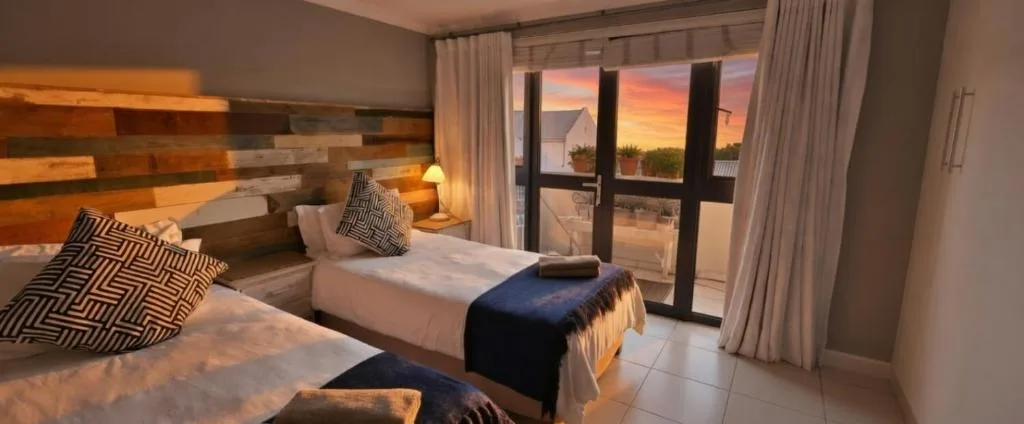 Spacious bedroom with twin beds and sunset views through large windows