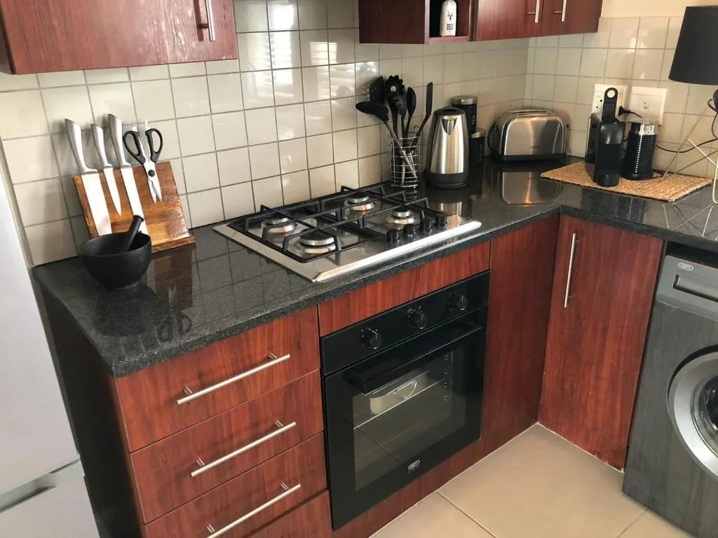 Modern kitchen with gas stove, dark countertops, and wooden cabinetry