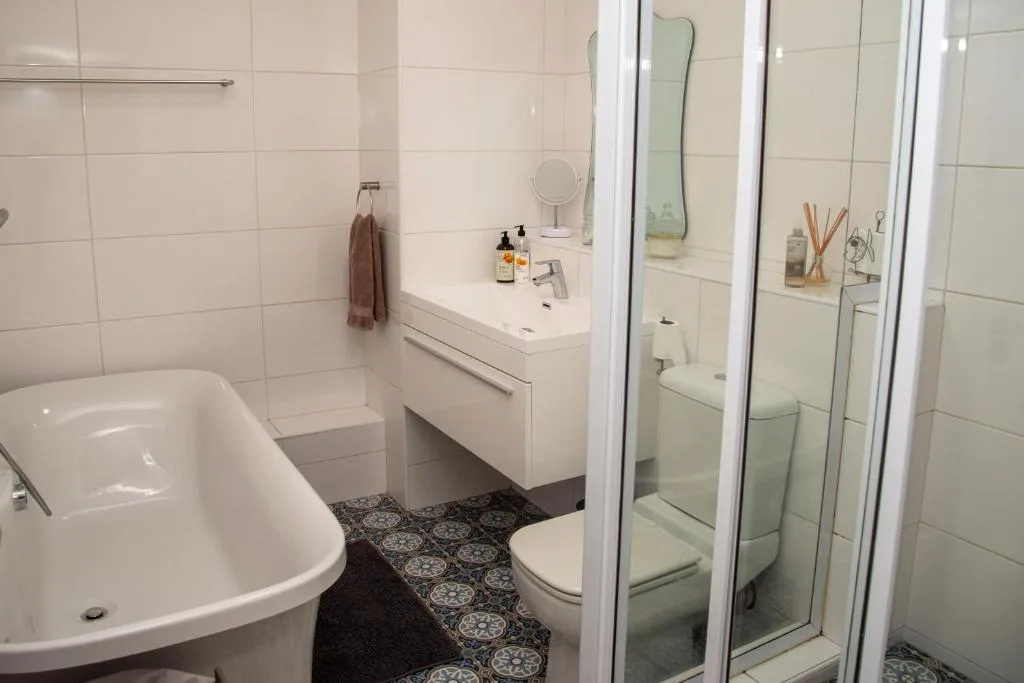 Modern bathroom with bathtub, vanity, toilet, and glass shower enclosure