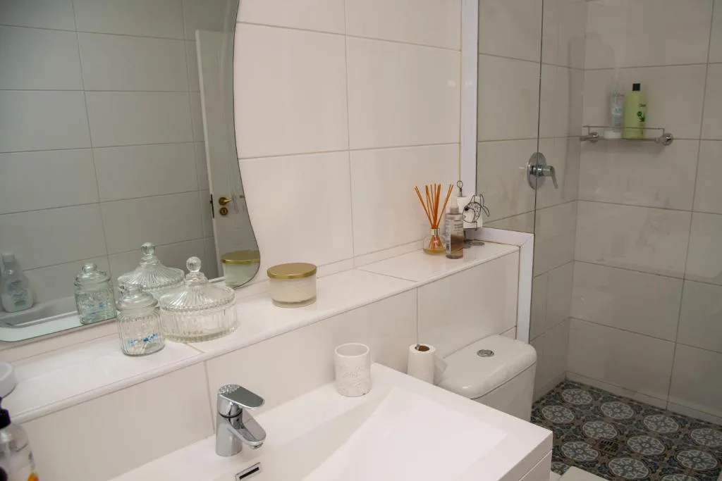 Clean modern bathroom with white vanity, mirror, toilet, and shower enclosure