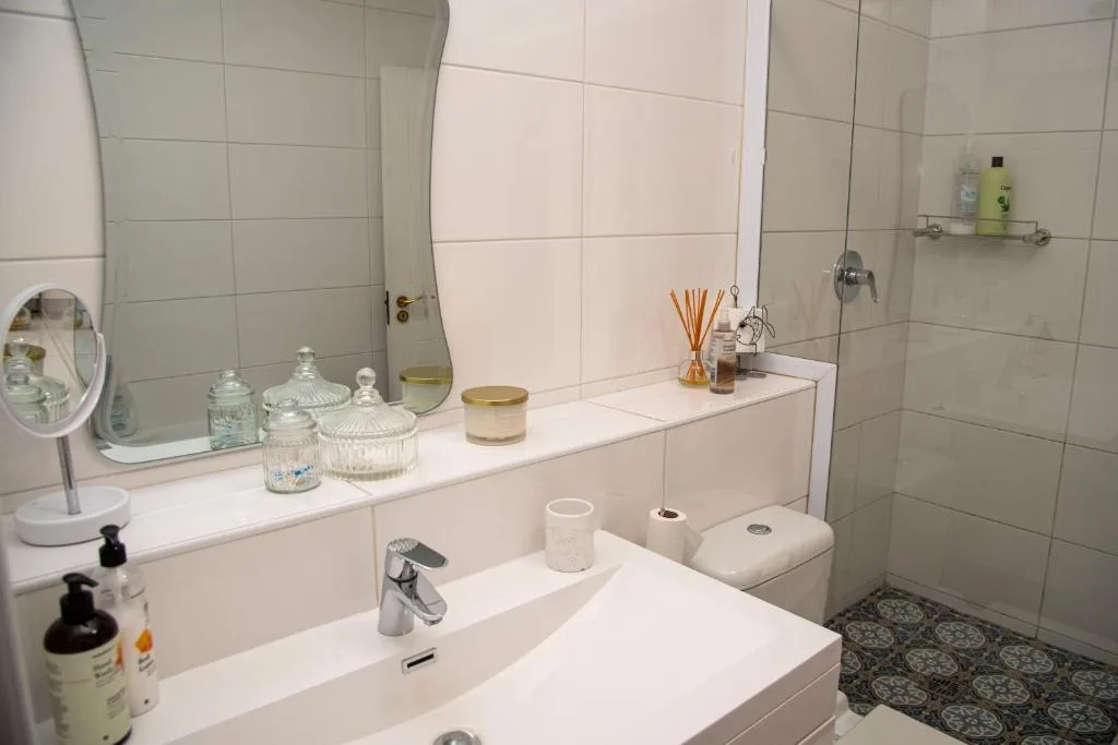 Clean modern bathroom with dual vanity, mirror, and tiled shower area