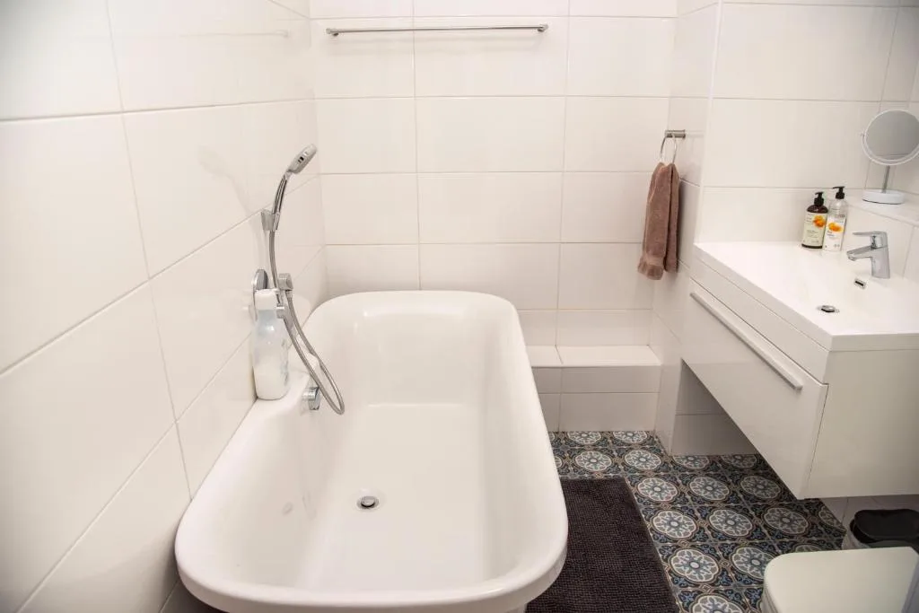 Clean white bathroom with freestanding bathtub, vanity sink, and decorative floor tiles