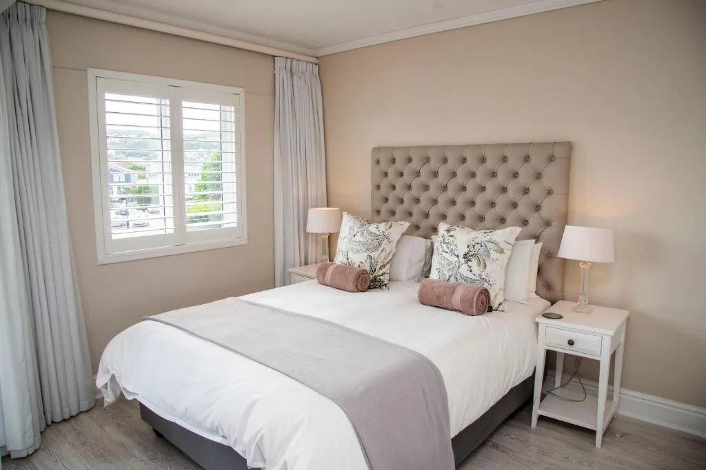 Elegantly appointed bedroom with tufted headboard and garden views