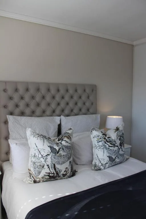 Bed with tufted headboard and decorative bird-print pillows