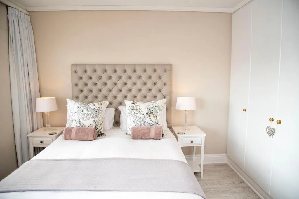 Bright bedroom with upholstered headboard, white linens, and twin bedside tables